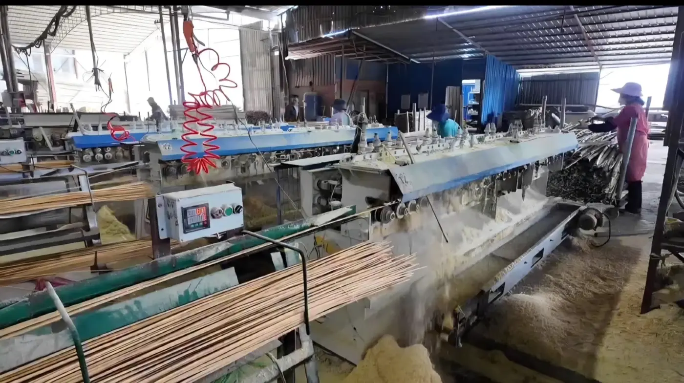 Bamboo filament size-setting machines running on the factory floor with sticks emerging onto racks